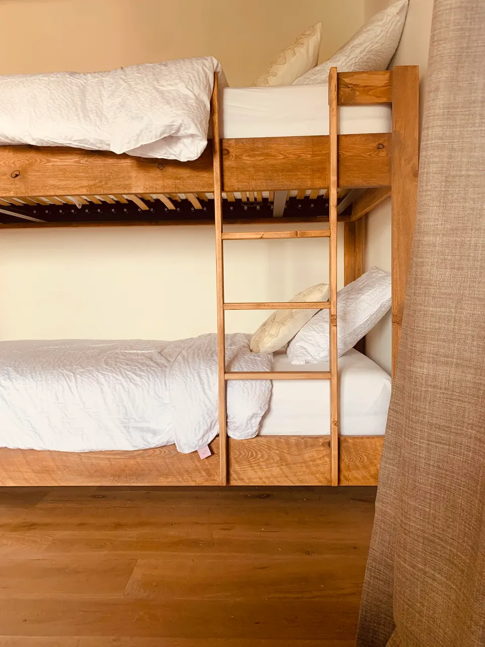 Wooden bunk bed with a ladder and white bedding