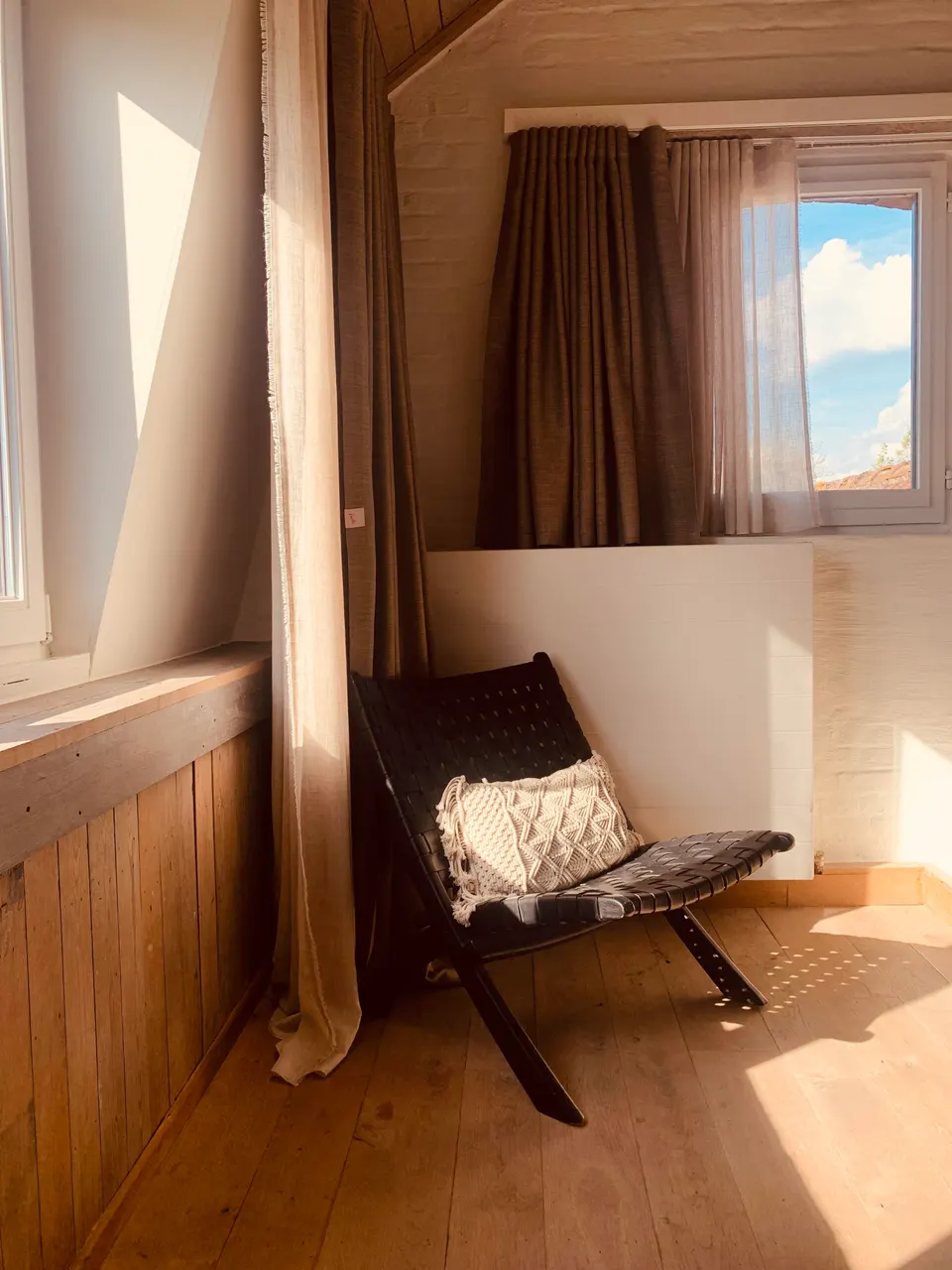 Leather folding chair with a cushion in a sunny corner of an attic room, by a curtained window
