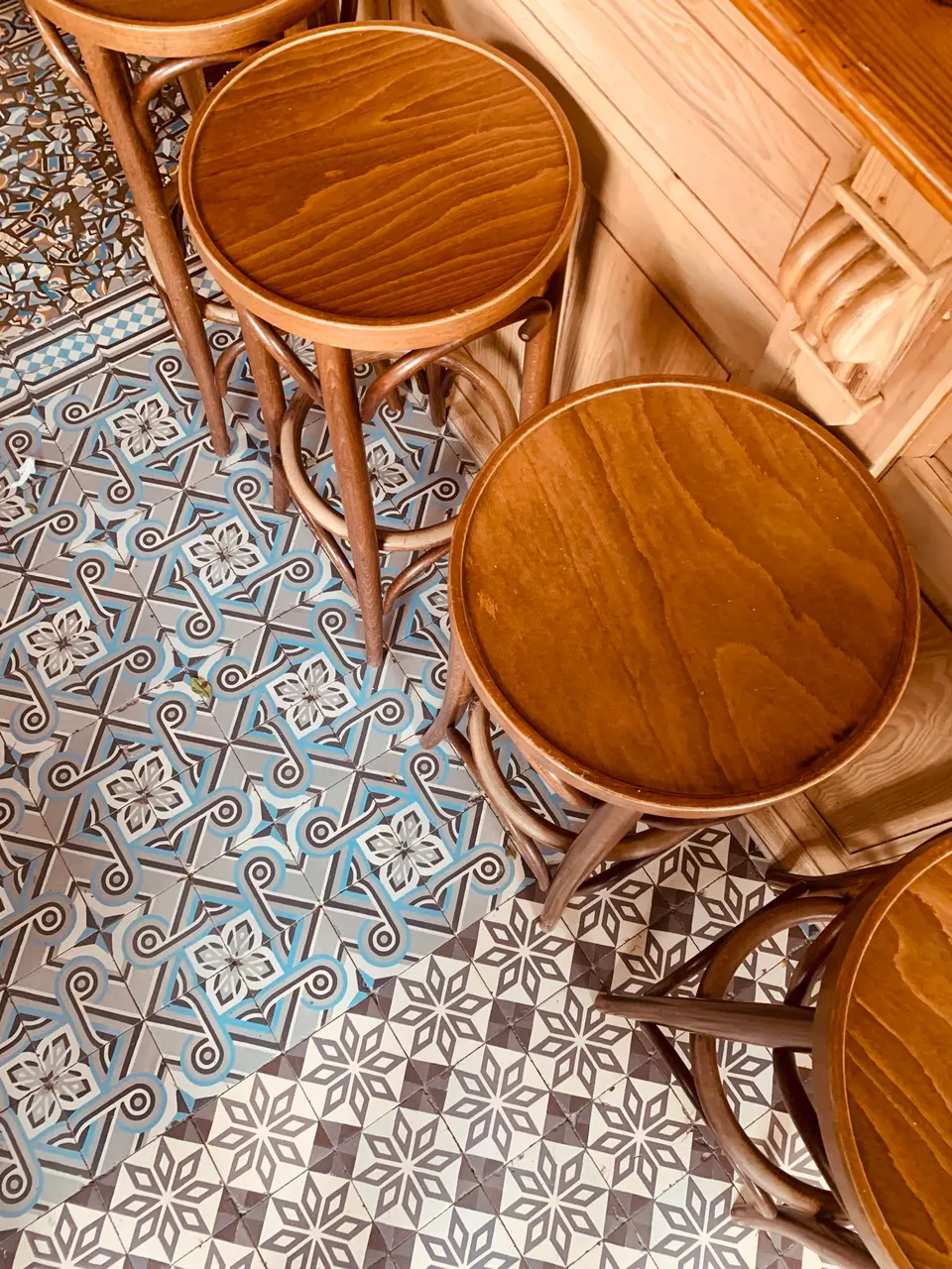 Wooden bar stools seen from above on a blue-grey cement-tile floor