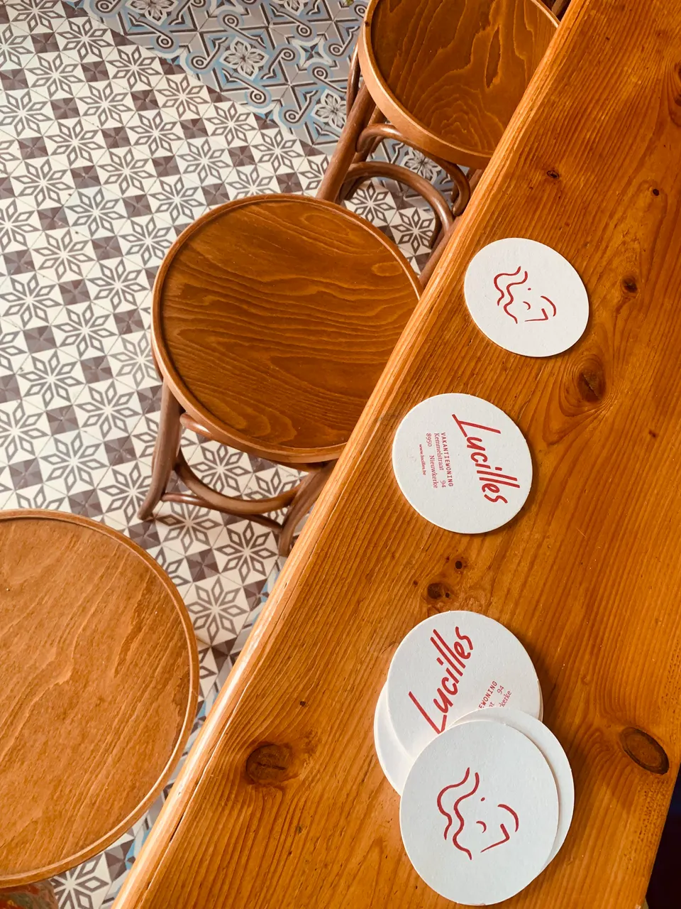Lucilles beer mats on the wooden bar, with bar stools and a cement-tile floor below