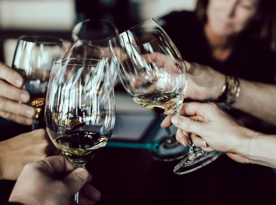 Hands clinking glasses of white wine