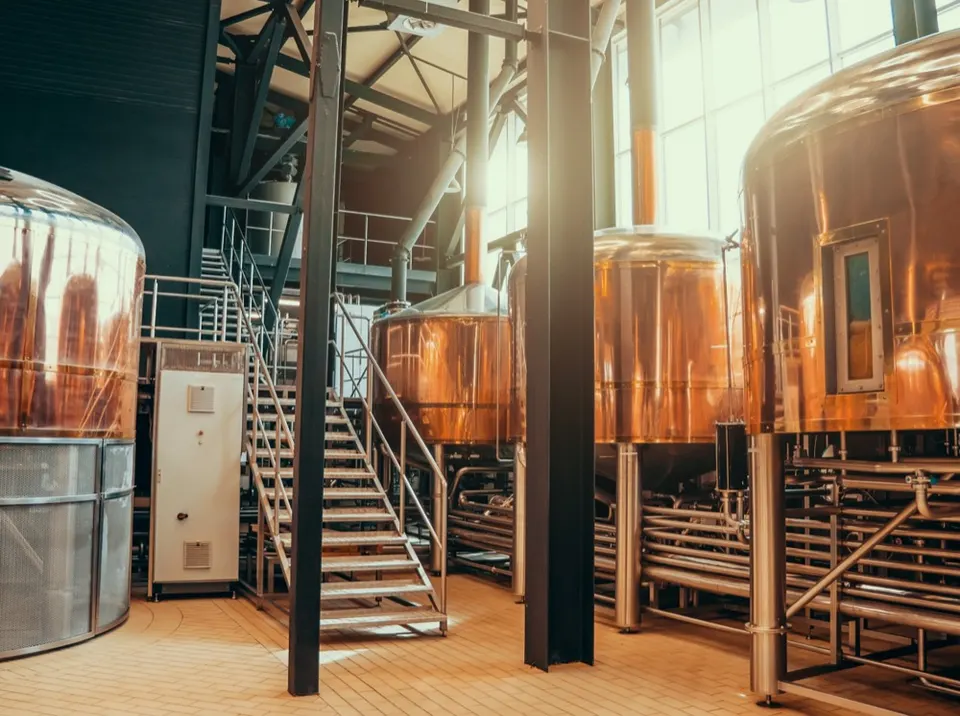 Brewhouse with copper brewing kettles, steel pipework and a staircase